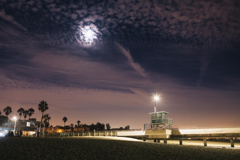 A photo of a full moon over a lifeguard stand on a beach